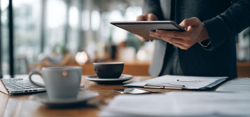 Business professional reviewing and approving documents on a tablet as an authorized signatory.